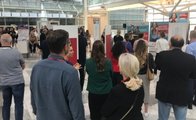 Besucher*innen stehen im allgemeinen Saal und folgen der Rede eines der Speaker auf der Messe.