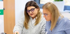 Angelina Keser und Dr. Simone Schnurr sitzen nebeneinander und tauschen sich aus mit Blick auf Unterlagen.