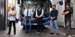 Fünf Männer posieren vor einem Bus. 