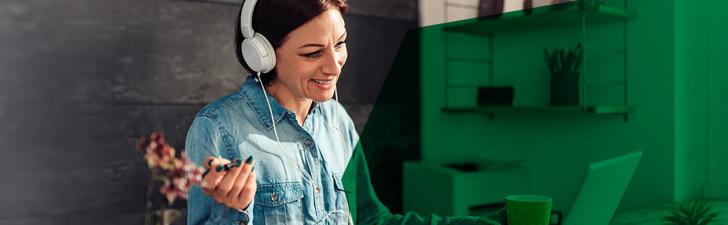 Headerbild: Lächelnde Frau mit Headset am Schreibtisch.