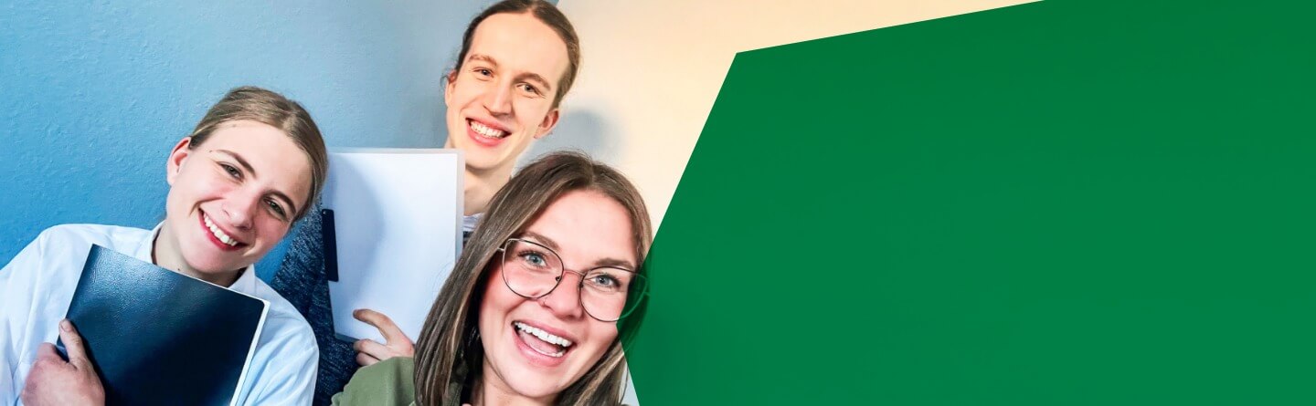 Berufsorientierung & Berufsvorbereitung Header: Drei Schüler*innen lachen in die Kamera, zwei von ihnen halten Hefter in den Händen, ein Mädchen hält den Daumen nach oben.