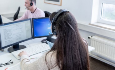 Zwei Personen, die vor einem Bildschirm sitzen.