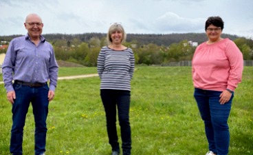 News- Bild: Drei Personen posieren auf einer Wiese