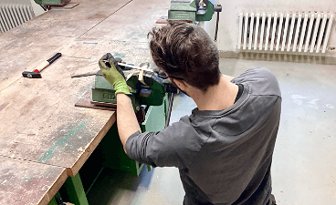 News- Bild: Ein von hinten fotografierter Mann arbeitet an einer Werkbank stehend