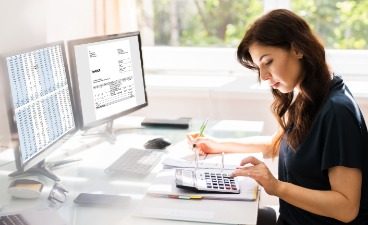 Einen Junge Frau arbeitet aufmerksam vor einem Computer an einem  Schreibtisch