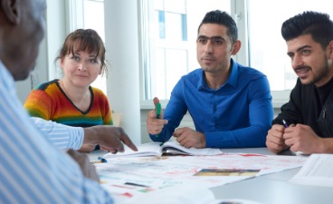 Drei Teilnehmer hören dem Lehrer im Kurs zu