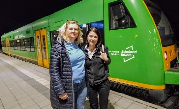 Ina Saldic und Anna Perehybenko vor einem Zug im Bayerischen Wald