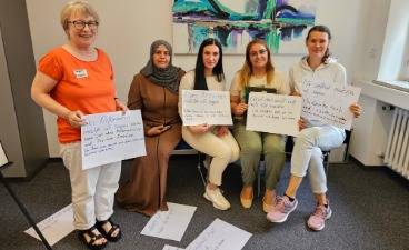 Mehrere Frauen sitzen beziehungsweise stehen vor der Kamera und halten Plakate hoch.